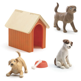 The Dolls' House - Dogs by Djeco includes a small plastic kennel with an orange frame and tan roof, three dog figurines in standing, sitting, and playful positions, a playful puppy and adult dog, plus a red food bowl and white bone.