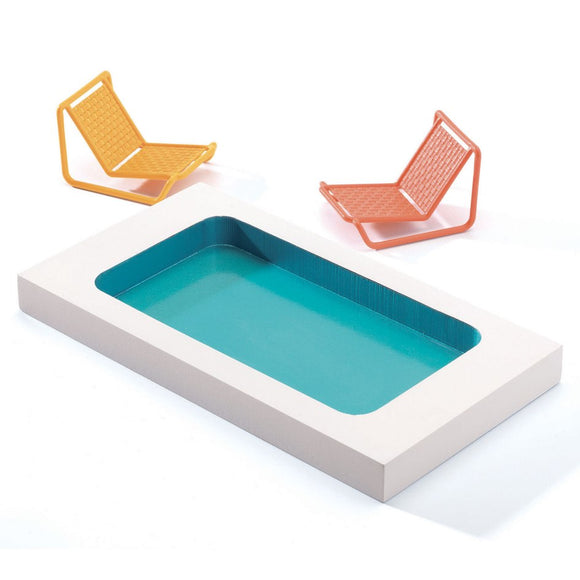 A minimalist scene, evocative of modern movement architecture, shows a small rectangular pool with aqua water and white borders. Two angular lounge chairs in yellow and orange beside the pool resemble the colorful furniture of the Djeco Dolls' House - City House. The background is a clean white.