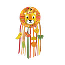 The Djeco DIY Lion Dreamcatcher features a vibrant round lion face with a crown, resembling a dream catcher. Colorful ribbons and hanging leaves in shades of red, orange, yellow, green, and brown dangle below the base.