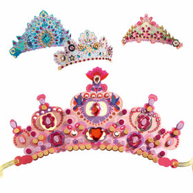 Four vibrant, ornate tiaras from Djeco's DIY Mosaic Tiaras set are displayed. The front tiara features pink and red gems with gold accents, resembling a glitter mosaic with gemstone stickers. The three in the background have unique blue, pink, purple, and gold designs with various patterns.