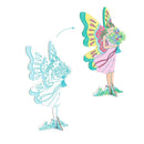 Illustration of a paper doll transformation in Djeco's Colour, Assemble & Play - Fairy World. On the left, an outlined fairy holds flowers; on the right, this enchanting character comes to life with vibrant yellow wings and a pink dress, standing on grass. An arrow indicates the magical shift from outline to color.