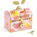 The Djeco Birds Money Box is a decorative wooden piggy bank featuring a floral design with birds and a heart-shaped lock. It includes two golden keys beside it, and coins can be deposited through the slot on top.