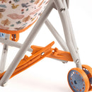 Close-up of a Djeco Stroller Forest reveals its foldable gray metal frame with an orange wheel lock, blue wheels, and a fabric seat ideal for dolls. The seat is adorned with pastel cartoon animals and trees, making it a charming doll accessory. Brand: Djeco.