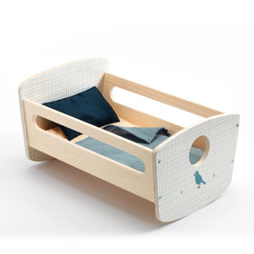 Introducing the Djeco Rocking Bed Cradle by Djeco: a compact baby doll bed made from natural wood, featuring grid-patterned headboards with an oval cutout. This charming cradle includes a dark teal pillow and a light teal blanket, both artfully arranged.