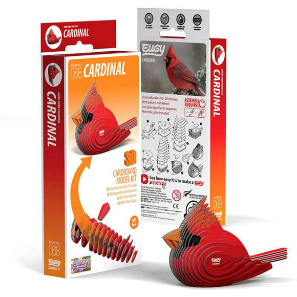 The image features the packaging for the EUGY Cardinal 3D cardboard model kit. The front prominently displays the completed songbird model, while the back provides assembly instructions and further product information. The packaging primarily uses red and white colors, reflecting the essence of EUGY figures.