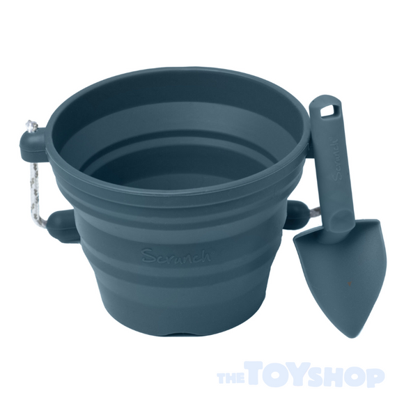 The Scrunch Mini Bucket & Spade set includes a collapsible French Navy silicone bucket with a rope handle and ridged design, plus a matching shovel. Both feature "Scrunch" and The Toy Shop logo, perfect for young gardeners.