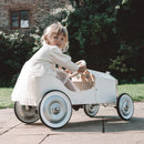 Child sitting in a vintage-style toy car outdoors