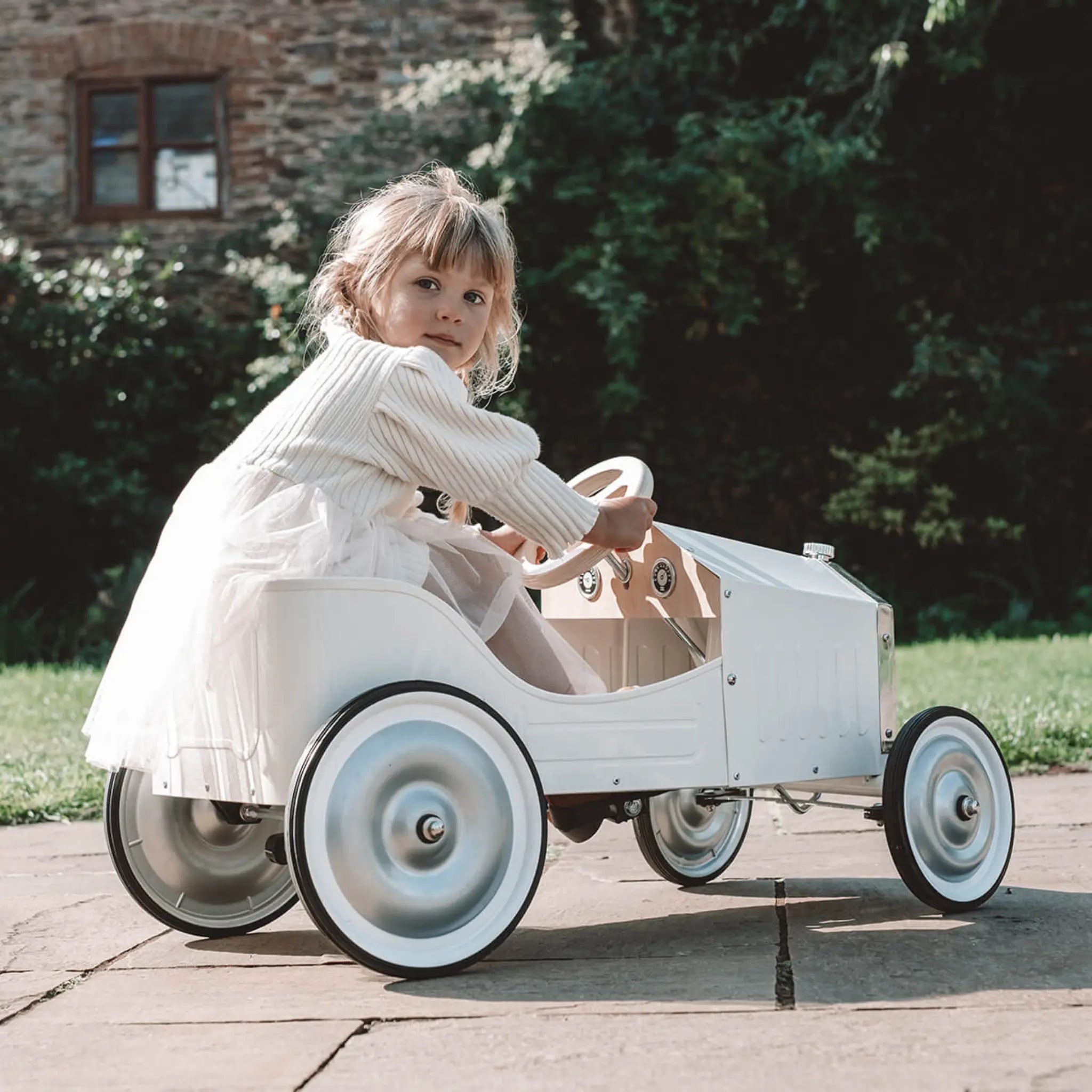 Child sitting in a vintage-style toy car outdoors