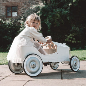 Child sitting in a vintage-style toy car outdoors