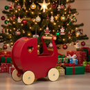 Red traditional doll's pram in front of a Christmas tree.