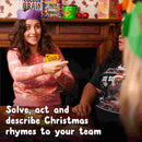 A woman wearing a purple paper crown and a festive sweater holds a card while smiling, seated at a table with others. Text at the bottom reads, "Solve, act, and describe Christmas rhymes to your team." Festive decorations are in the background, setting the perfect scene for playing Santa Banter by The Toy Shop—an entertaining Christmas game.