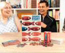 Two people sit at a table, beaming as they enjoy "Sounds Fishy" by Big Potato, an engaging trivia game featuring a fun bluffing aspect. The box showcases vibrant fish illustrations, with various game pieces spread across the table. Bookshelves in the background enhance the cozy atmosphere.
