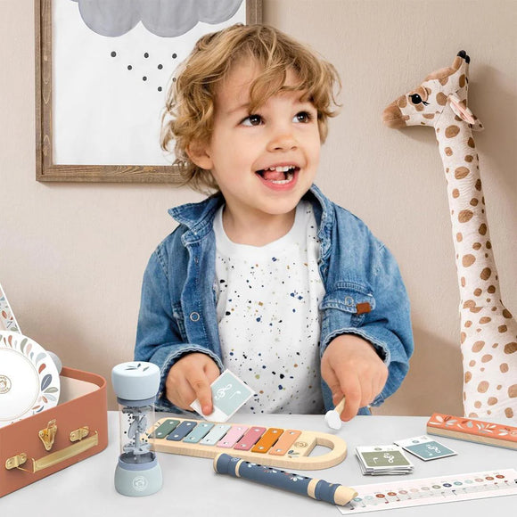 Child playing with a toy xylophone in a room with a giraffe plush toy and framed picture.