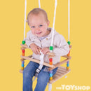 Small child in wooden cradle swing. Yellow background.