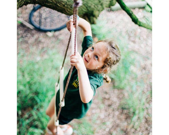 Looking down at a girl who is climbing up a rope ladder.