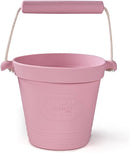 The BIGJIGS Foldable Activity Buckets in blush pink have a rope handle and an embossed logo, made from eco-friendly silicone for peace of mind.