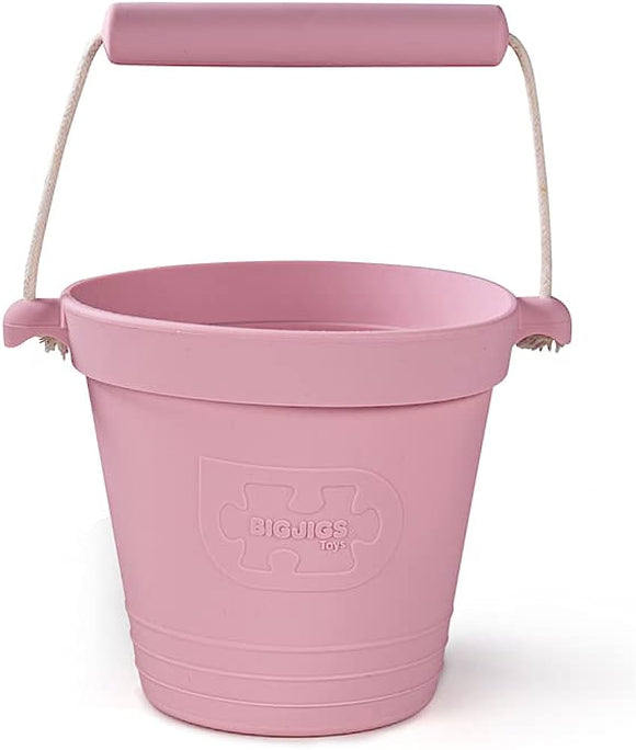 The BIGJIGS Foldable Activity Buckets in blush pink have a rope handle and an embossed logo, made from eco-friendly silicone for peace of mind.