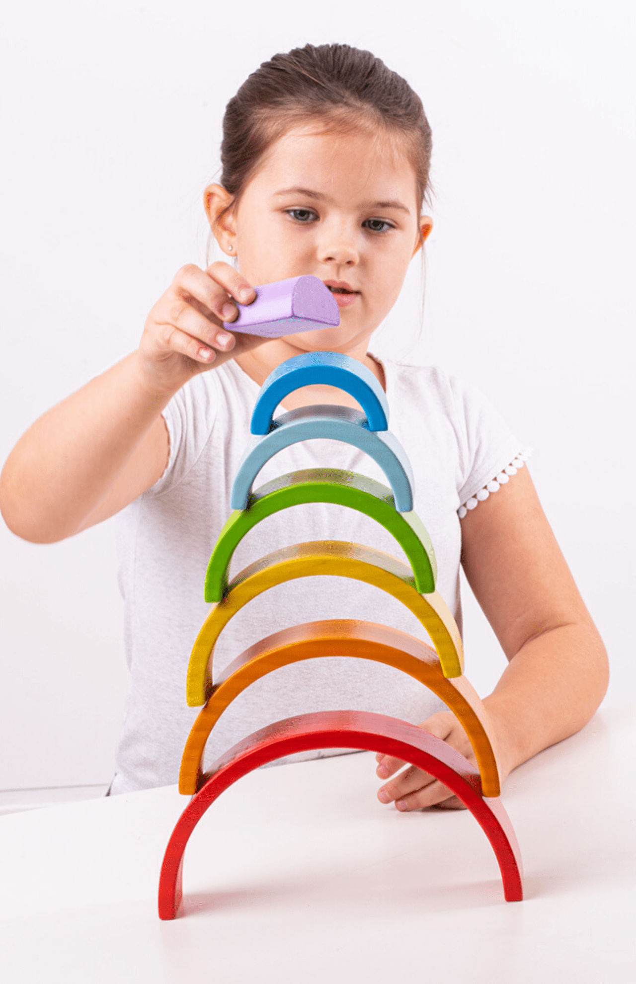 Girl stacking rainbow arches.