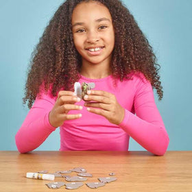 Girl in long sleeved pink t-shirt putting the cardboard parts of the koala figure together.