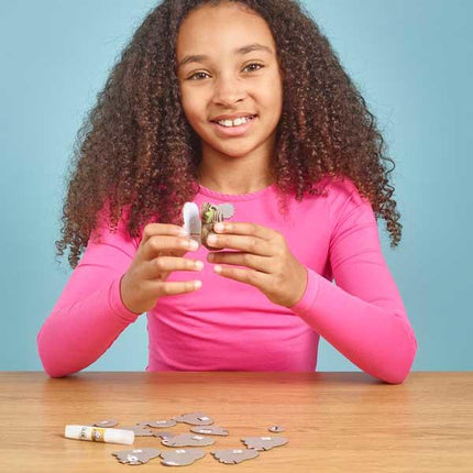 Girl in long sleeved pink t-shirt putting the cardboard parts of the koala figure together.
