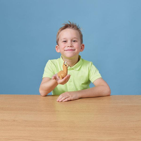 Boy with pale green polo shirt holding out llama model in one hand.
