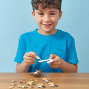 Boy in blue tshirt sitting at a table and sticking the meerkat model together.