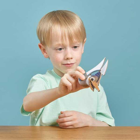 Boy with blonde hair and mint green tshirt playing with the flying pterodactyl model.