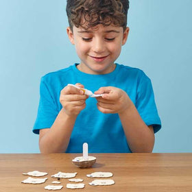 Boy with blue tshirt glueing parts of the cardboard sheep model together.