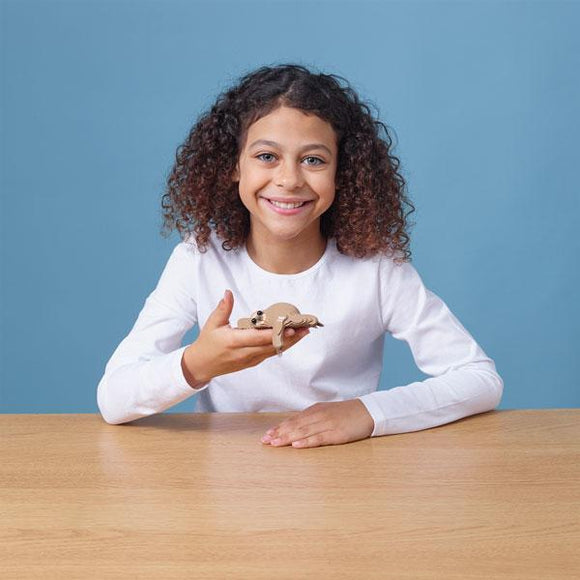 Girl with dark hair and long sleeve white t-shirt holding out the eugy sloth model.