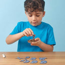 Boy in blue tshirt sitting at a table and slotting and sticking the whale shark model pieces together.