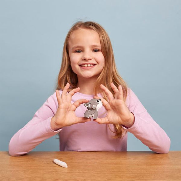 Blonde girl in long sleeved pink top holing completed wolf model in both hands.