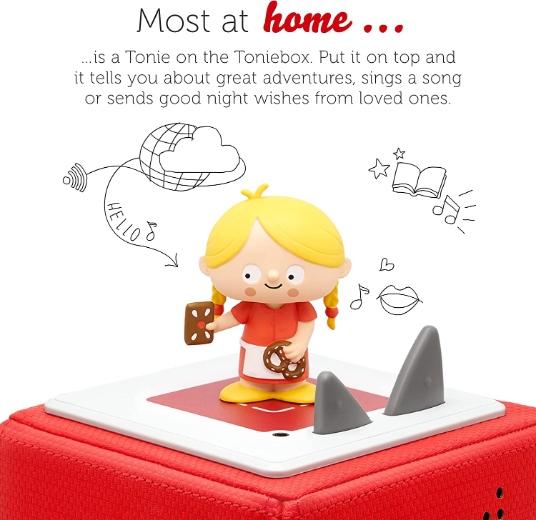 Gretel figure from the Hansel and gretel Tonie. She is wearing a red dresss, yellow hair and standing on top of  a Toniebox.