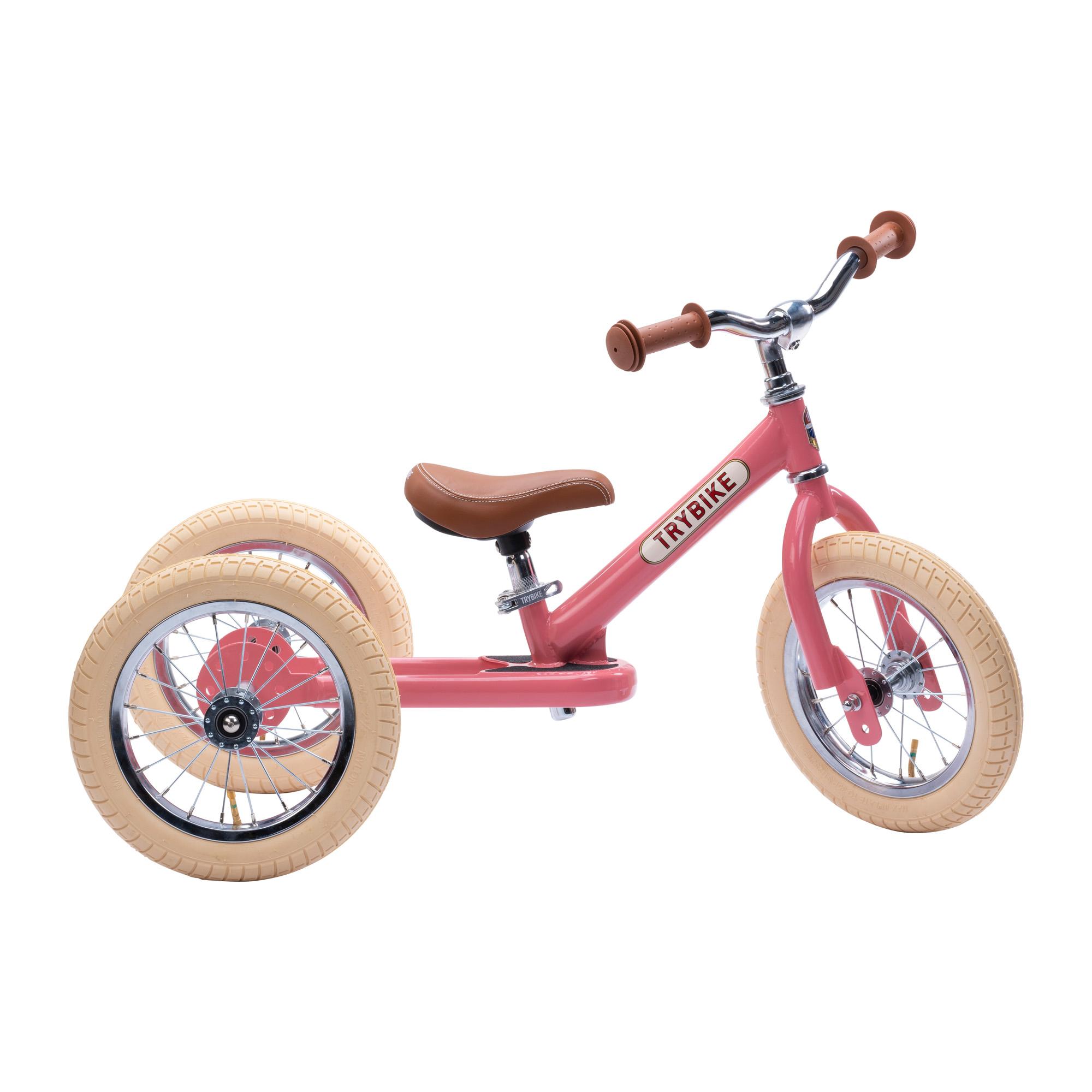 Side view of pink trybike with cream tyres and brown leather-look seat and handles.