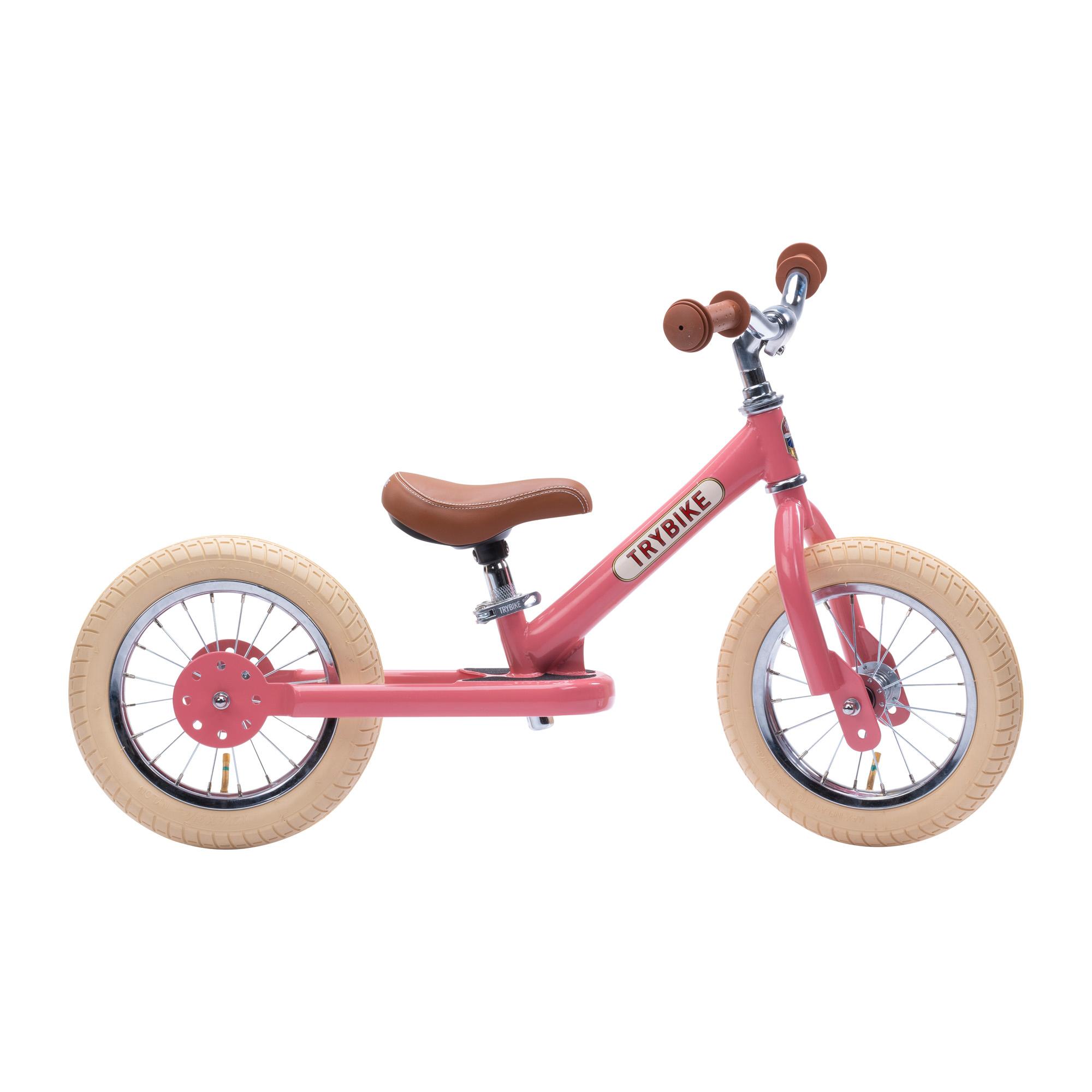 Side view of pink Trybike on white background.