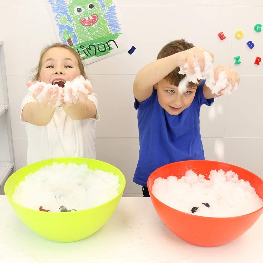 Children with a green bowl and a red bowl in front of them making snow balls.
